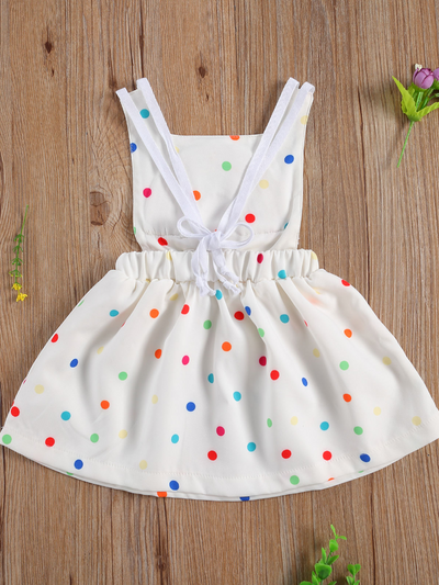 Baby white dress has a colorful polka dot print and rainbow applique pullover style ties at the back