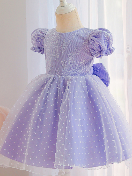 Baby dress has capped sleeves and embroidered tulle overlay bodice and swiss tulle overlay skirt, big bow accent at the back