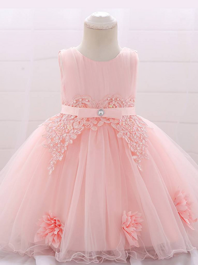 Baby dress has a tulle overlay with flower applique and a satin belt with rhinestone detail-pink