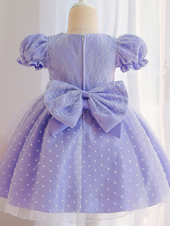 Baby dress has capped sleeves and embroidered tulle overlay bodice and swiss tulle overlay skirt, big bow accent at the back