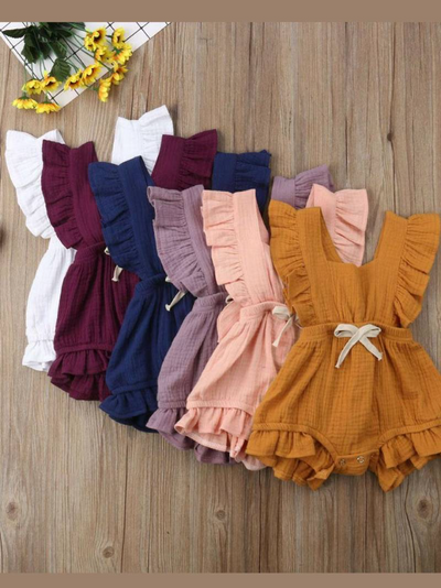 Baby bohemian Overall style romper onesie that ties in the back and has a drawstring at the waist. Little ruffled adorn the shoulder and short hem