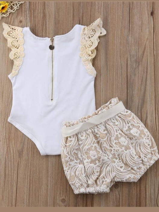 Baby set features a short-sleeved onesie with a crochet ruffle at the shoulder and embroidered shorts with a sash
