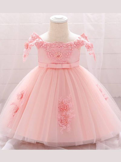 Baby dress has a satin embroidered bodice with pearl details and capped sleeves, a bow belt at the waist, and a tulle skirt with flower applique