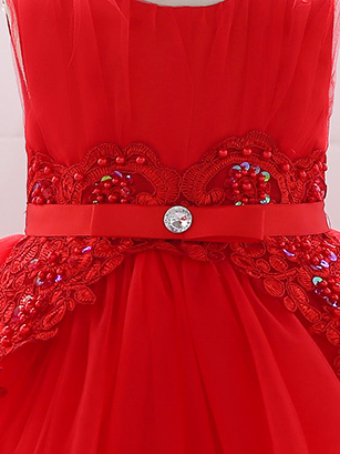 Baby dress has a tulle overlay with flower applique and a satin belt with rhinestone detail-red