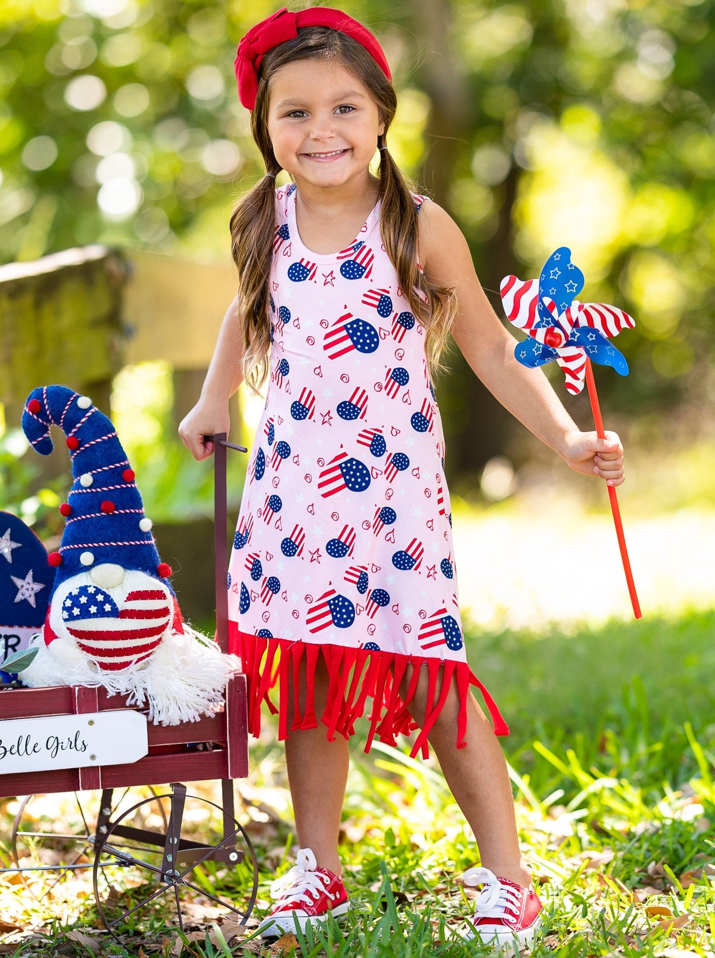 Girls pink dress features an Americana print with fun fringes at the hem