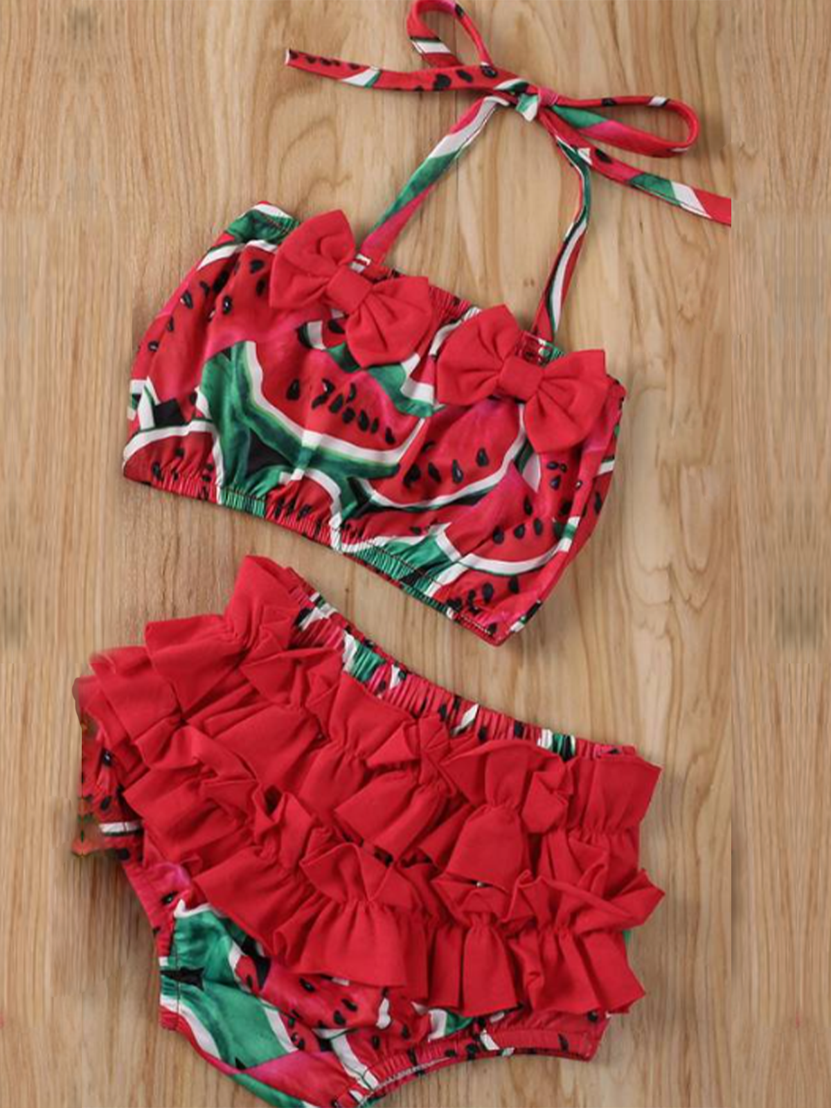 Baby swimsuit features a top with a fruit print and an adjustable halter style strap with ruffles bottoms