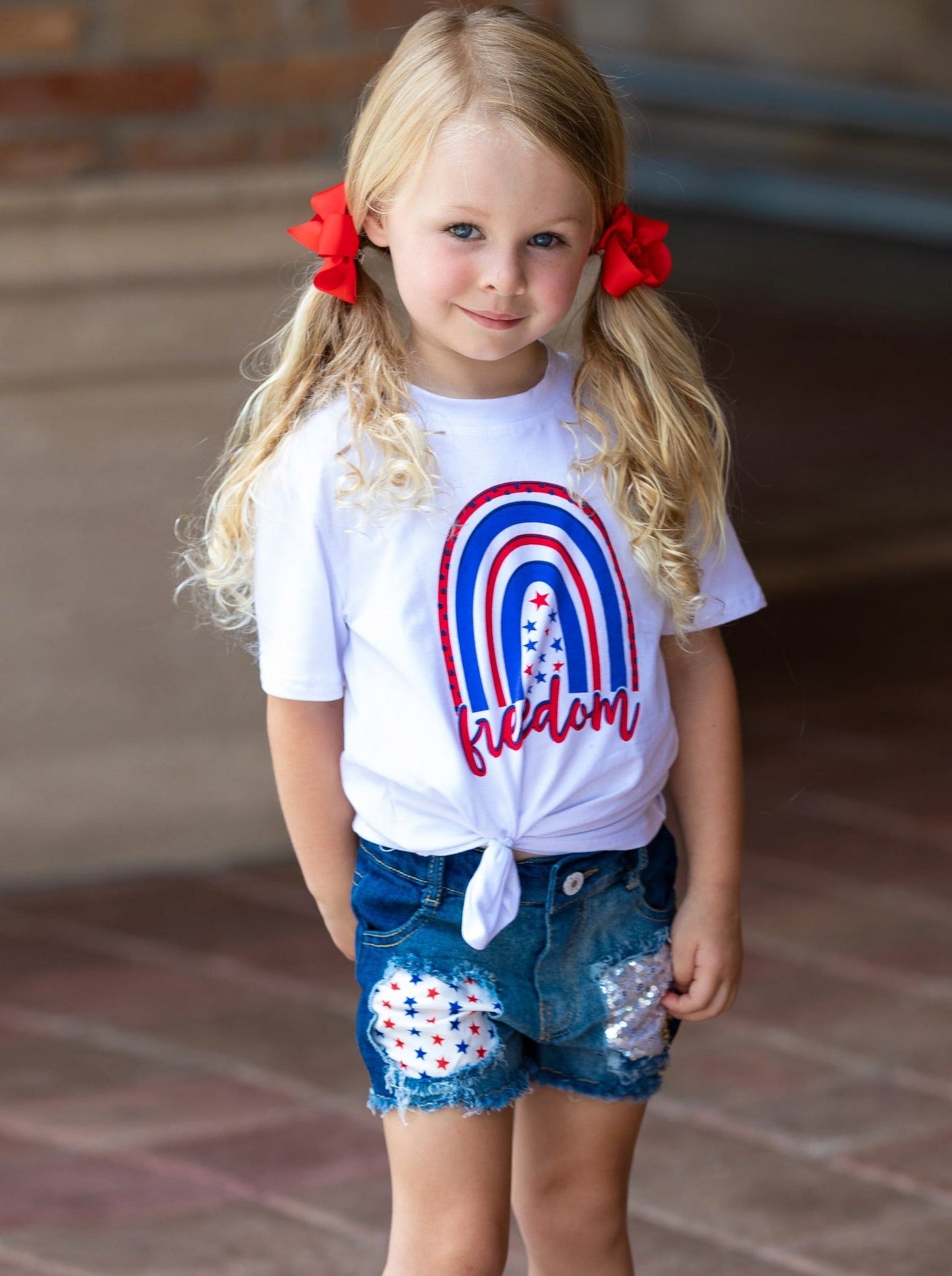 Girls set features a white top with "Freedom" print and patched denim shorts with a red sash