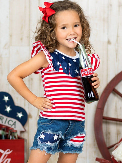 Girls 4th of July set features an American flag print flutter sleeve top with fringe neckline and patched denim shorts with a sash