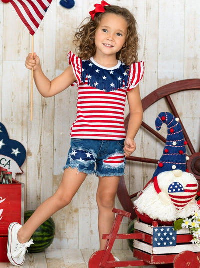 Girls 4th of July set features an American flag print flutter sleeve top with fringe neckline and patched denim shorts with a sash