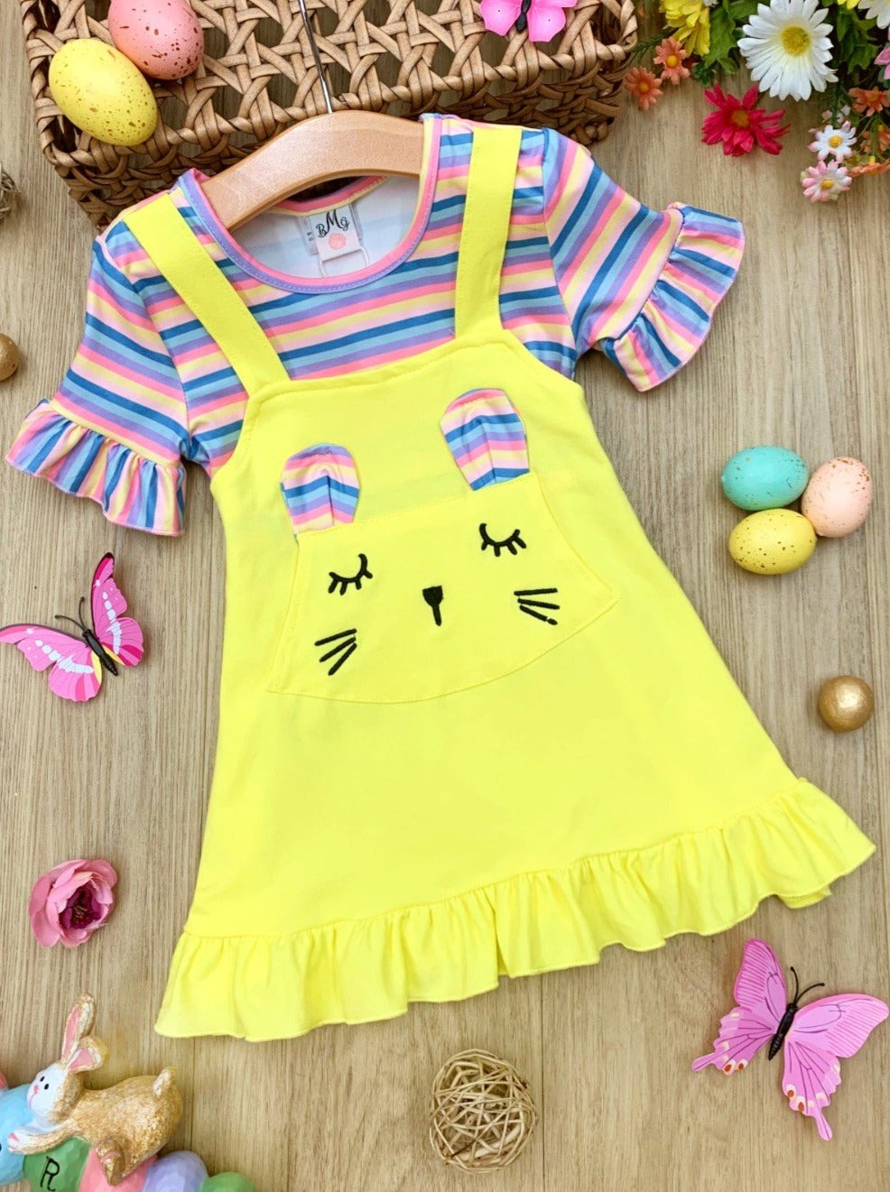 Girls Easter Dress features a striped top with ruffled short sleeves and an overall skirt with a front kangaroo pocket and bunny face and bunny ears- pink 2T to 10Y