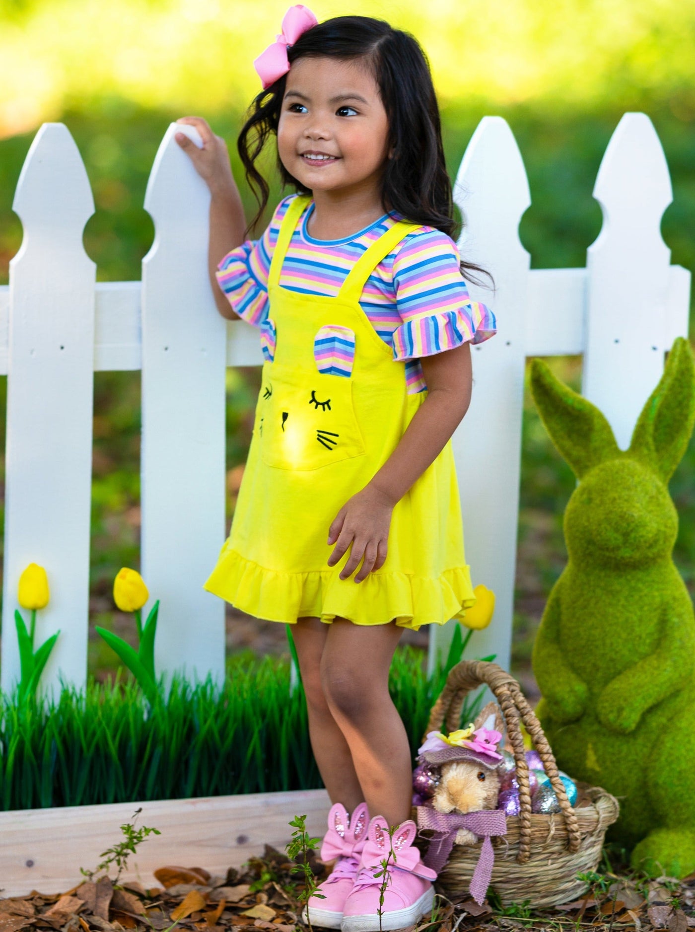 Girls Easter Dress features a striped top with ruffled short sleeves and an overall skirt with a front kangaroo pocket and bunny face and bunny ears- pink 2T to 10Y