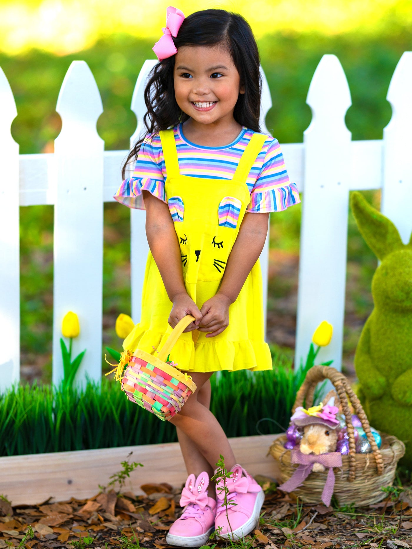 Girls Easter Dress features a striped top with ruffled short sleeves and an overall skirt with a front kangaroo pocket and bunny face and bunny ears- pink 2T to 10Y