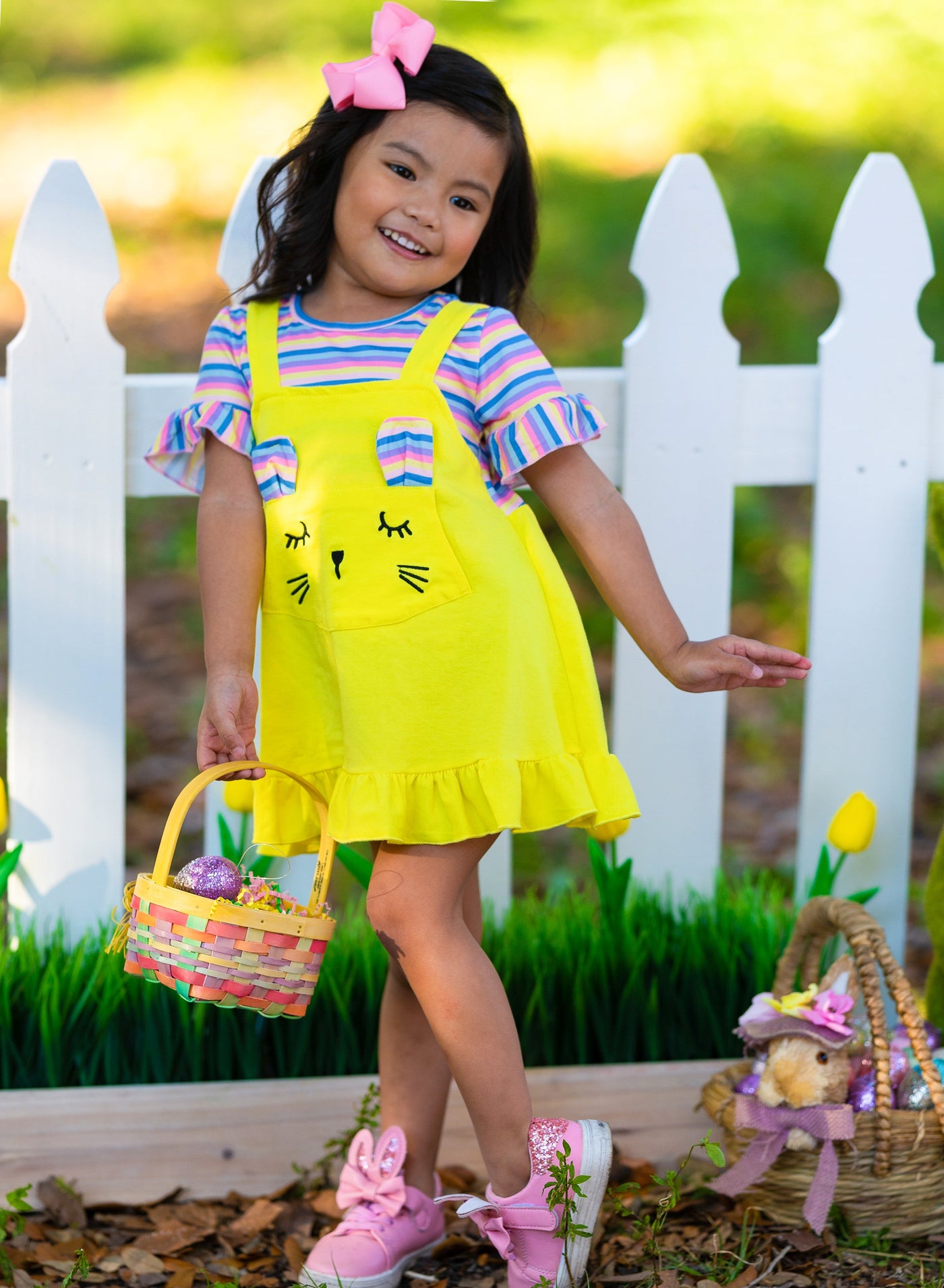 Girls Easter Dress features a striped top with ruffled short sleeves and an overall skirt with a front kangaroo pocket and bunny face and bunny ears- pink 2T to 10Y