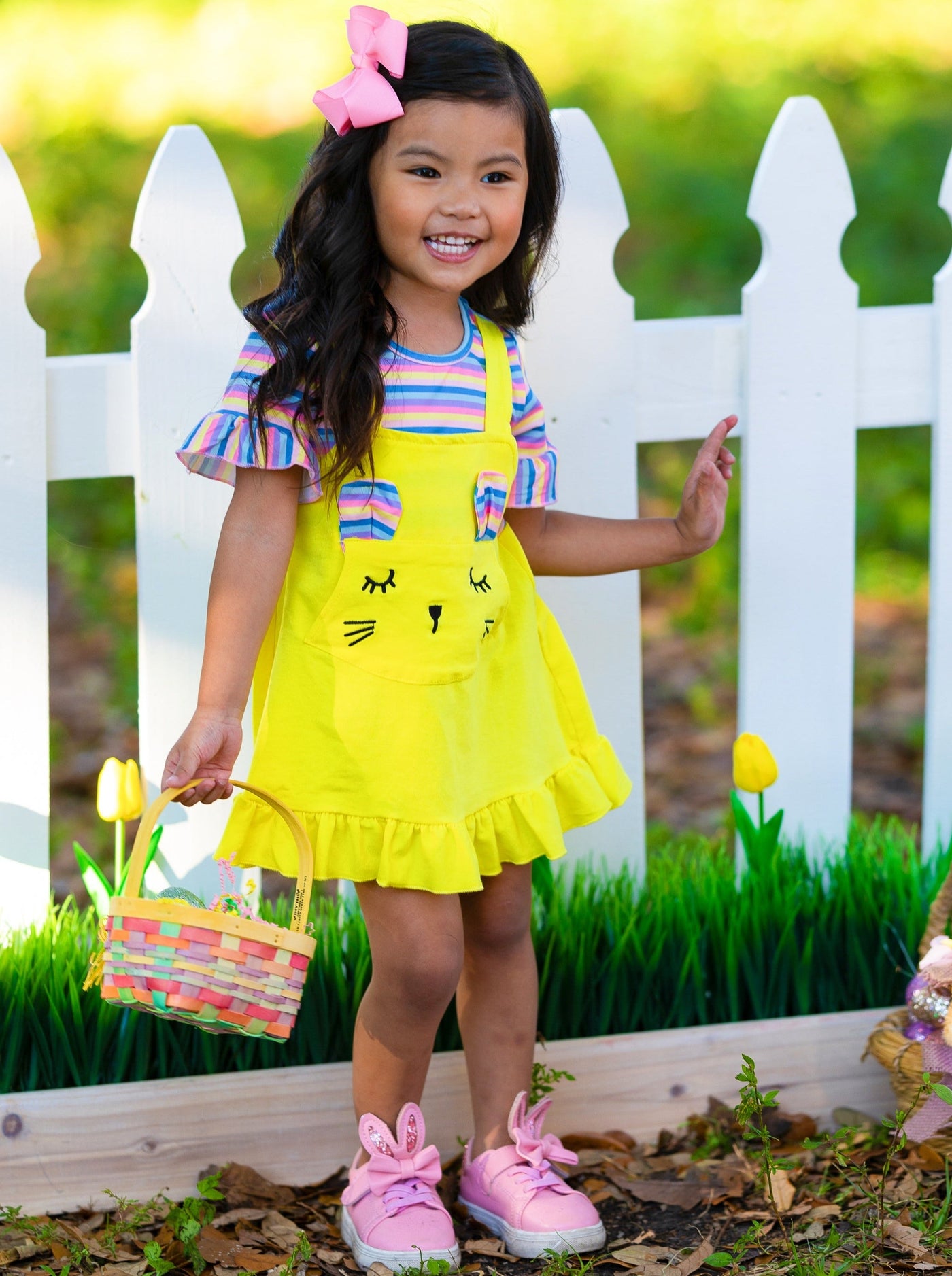 Girls Easter Dress features a striped top with ruffled short sleeves and an overall skirt with a front kangaroo pocket and bunny face and bunny ears- pink 2T to 10Y