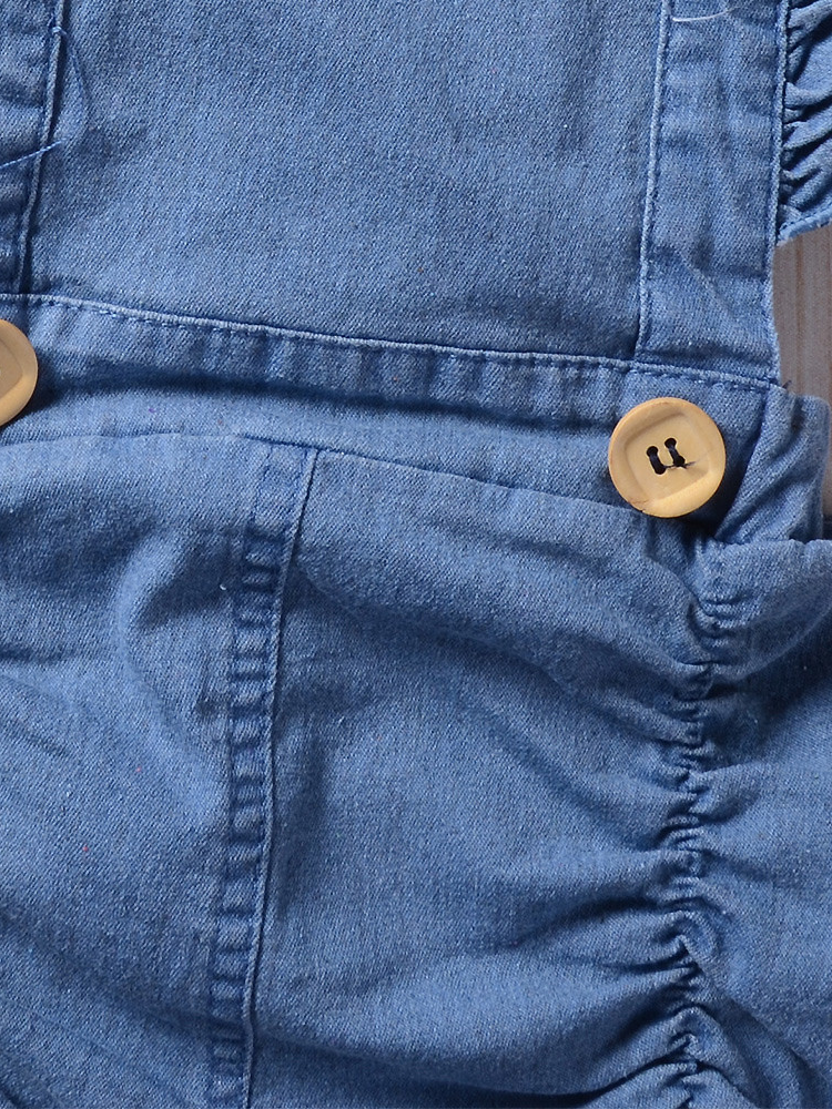 Baby overall style romper onesie has ruffled shoulder straps that tie on the back. has 2 little buttons on the front to make it even more stylish