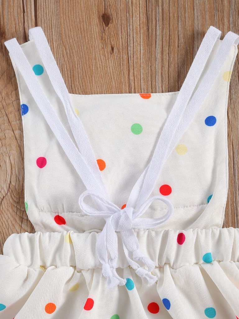 Baby white dress has a colorful polka dot print and rainbow applique pullover style ties at the back