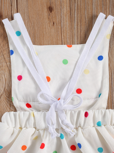 Baby white dress has a colorful polka dot print and rainbow applique pullover style ties at the back