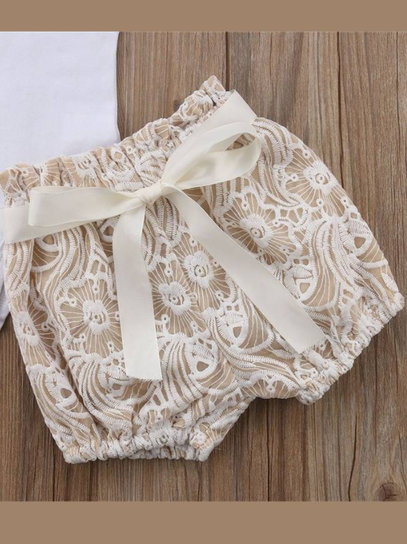 Baby set features a short-sleeved onesie with a crochet ruffle at the shoulder and embroidered shorts with a sash