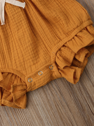 Baby bohemian Overall style romper onesie that ties in the back and has a drawstring at the waist. Little ruffled adorn the shoulder and short hem