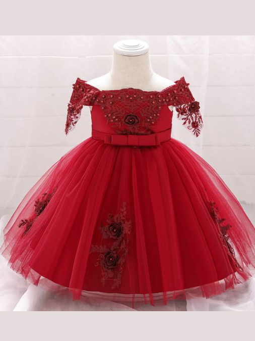 Baby dress has a satin embroidered bodice with pearl details and capped sleeves, a bow belt at the waist, and a tulle skirt with flower applique