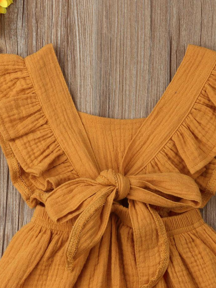 Baby bohemian Overall style romper onesie that ties in the back and has a drawstring at the waist. Little ruffled adorn the shoulder and short hem