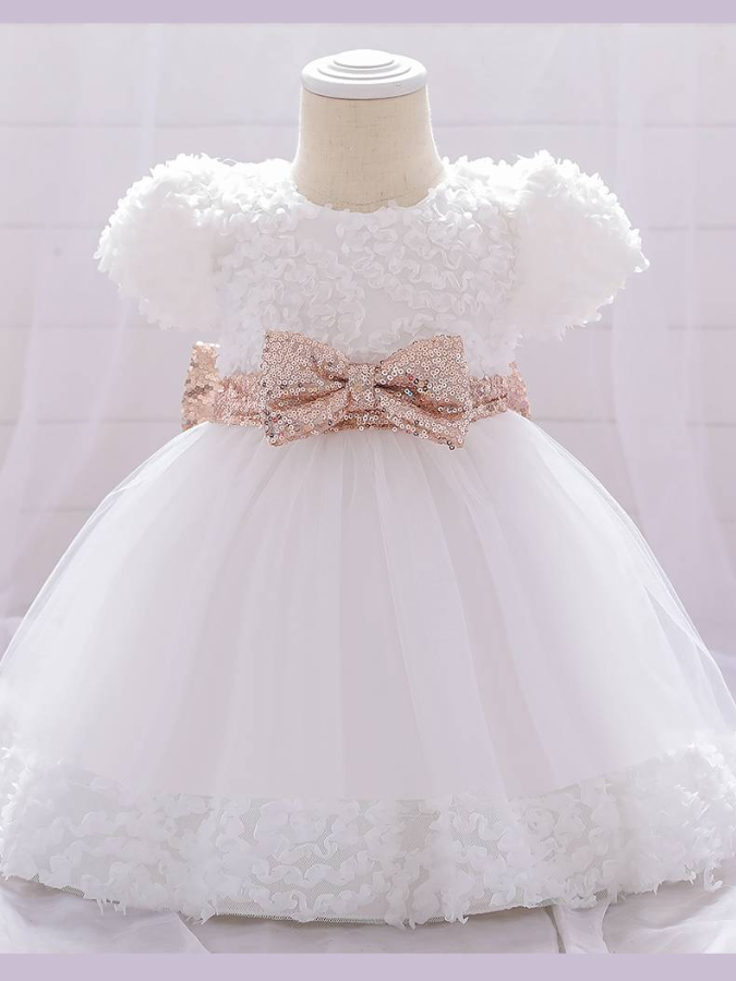 Baby dress has a floral bodice, a tulle skirt with floral hem, and a gold sequin belt with bow at the front and back