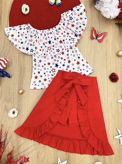 Girls three piece set features a white ruffle top with red and blue star print and red shorts with matching overlay wrap ruffle skirt